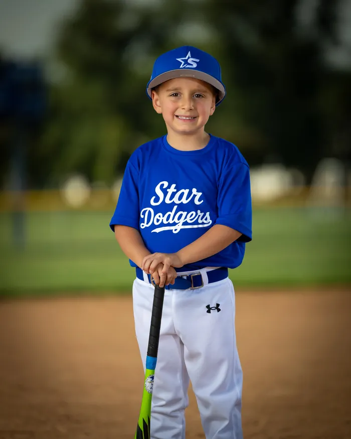 Star Dodgers tee ball player smiling with a bat on home plate, Star Idaho