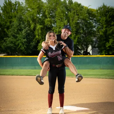 Idaho Batbusters 16U softball player giving coach a piggyback ride
