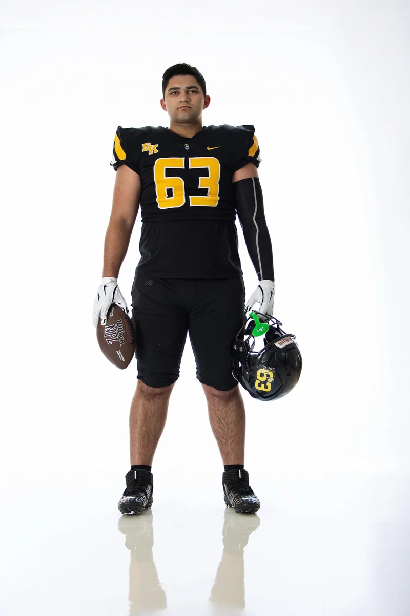Football player game ready for sports portraits: full uniform, helmet, gloves, football