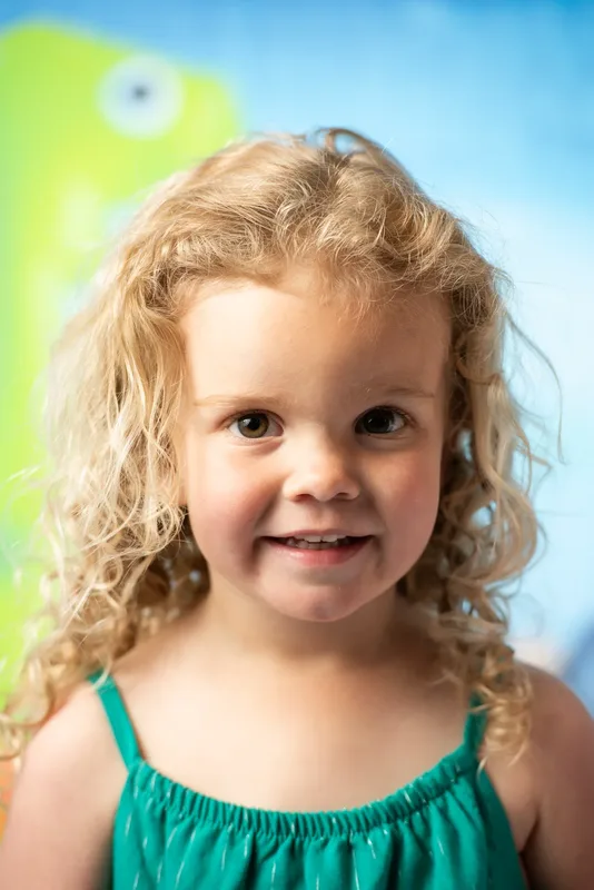 Toddler with curly hair smiling for daycare photo day portrait - preschool photographer Treasure Valley Idaho