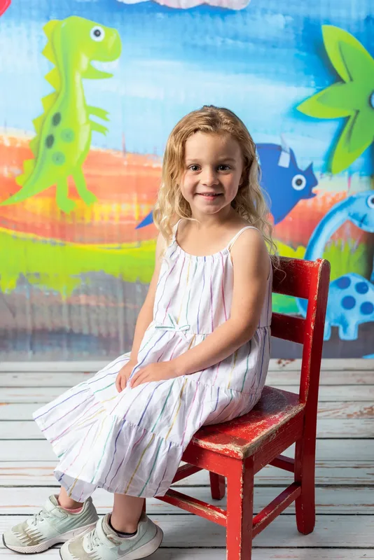 Preschool girl seated on red wooden chair for photo day portrait - daycare photography Treasure Valley