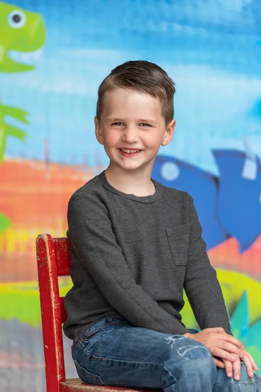 Young boy seated on vintage red chair for preschool photo day portrait - Treasure Valley school photographer