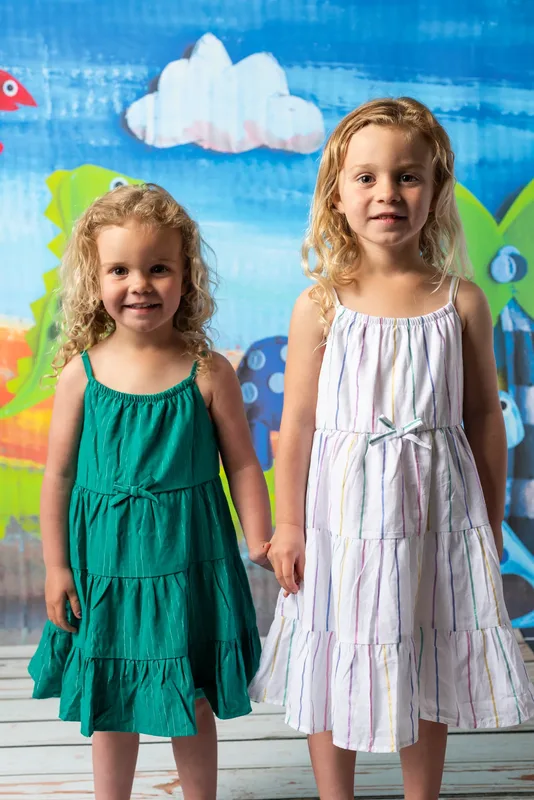 Two young sisters holding hands in sundresses at daycare photo day - sibling portraits Treasure Valley Idaho