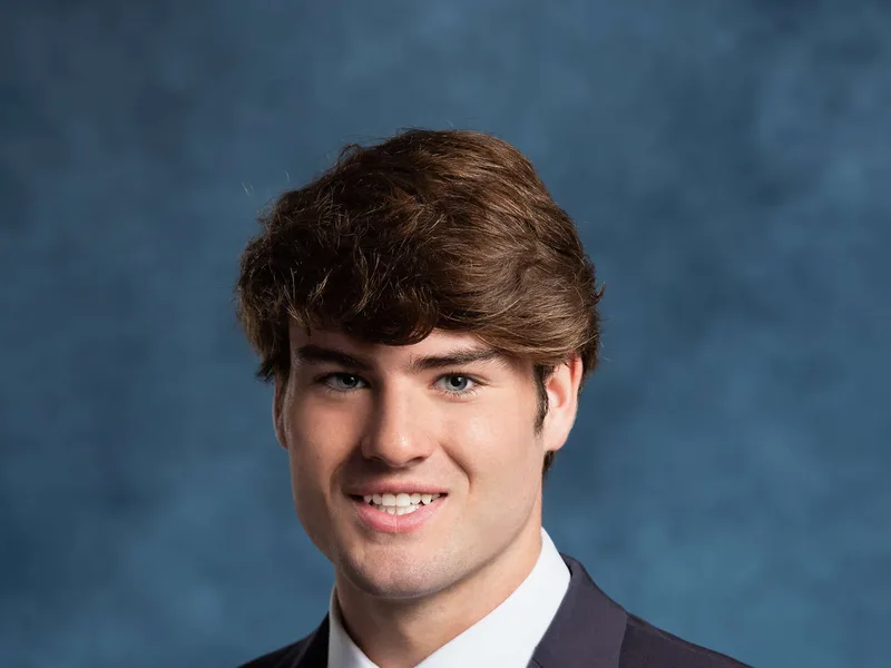 Formal senior portrait in navy suit and tie with blue studio backdrop Treasure Valley